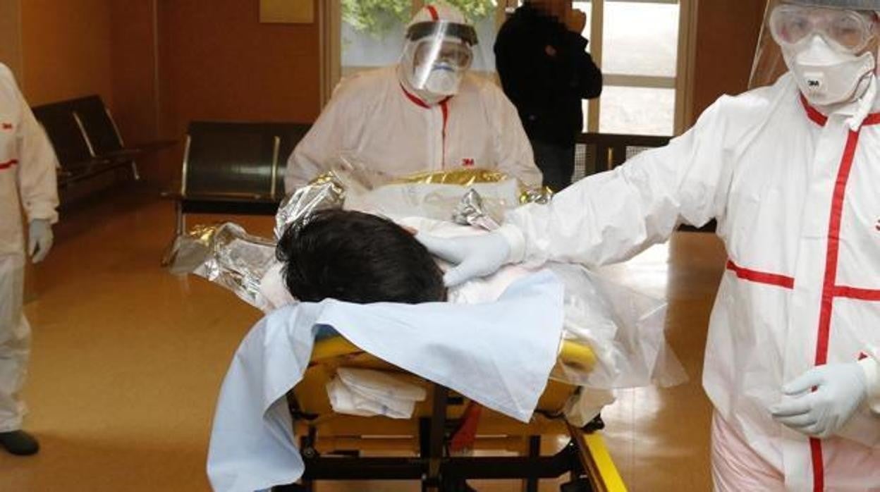 Sanitarios con traje de protección contra el coronavirus atienden a un paciente