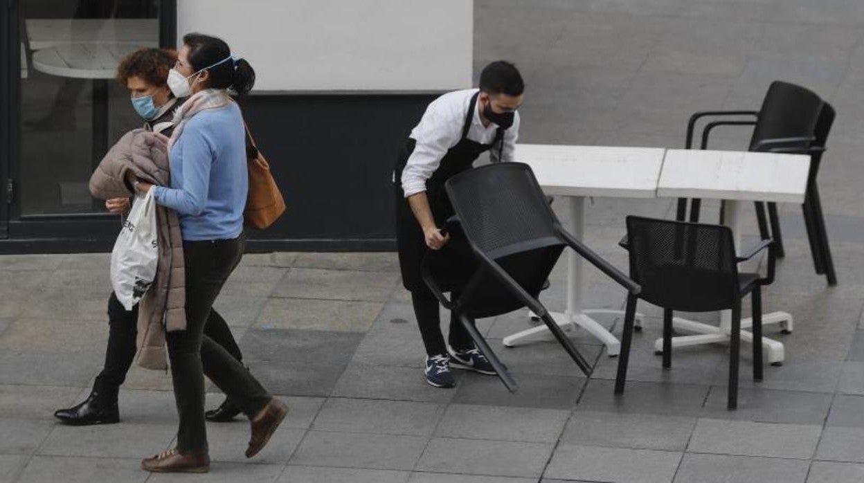 Un camarero en Sevilla se dispone a recoger las sillas por el cierre de su establecimiento ante las medidas del Covid