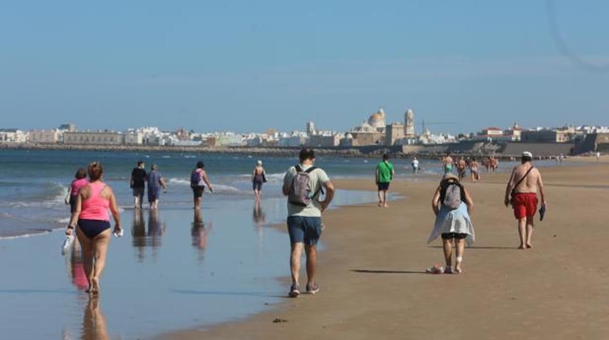 Varias personas pasean por la playa de Cádiz