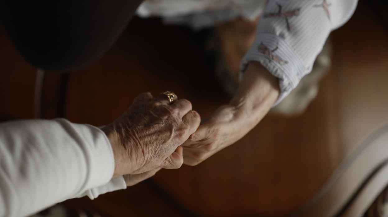 Una mujer asiste a una persona mayor en su casa en Córdoba