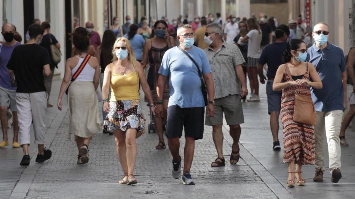 Varias personas pasean por la calle de Sevilla con la mascarilla puesta, algo que no será obligatorio desde este sábado