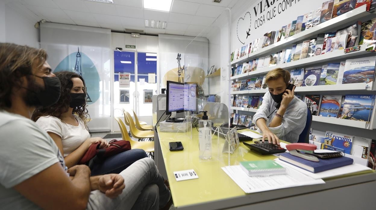 El responsable de la agencia de viajes Palmasur atiende a unos clientes para reservar las vacaciones de verano