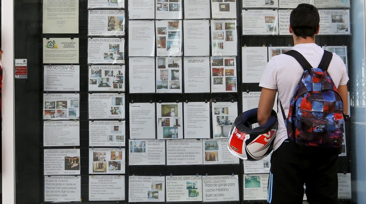 Un joven mira anuncios en la puerta de una inmobiliaria