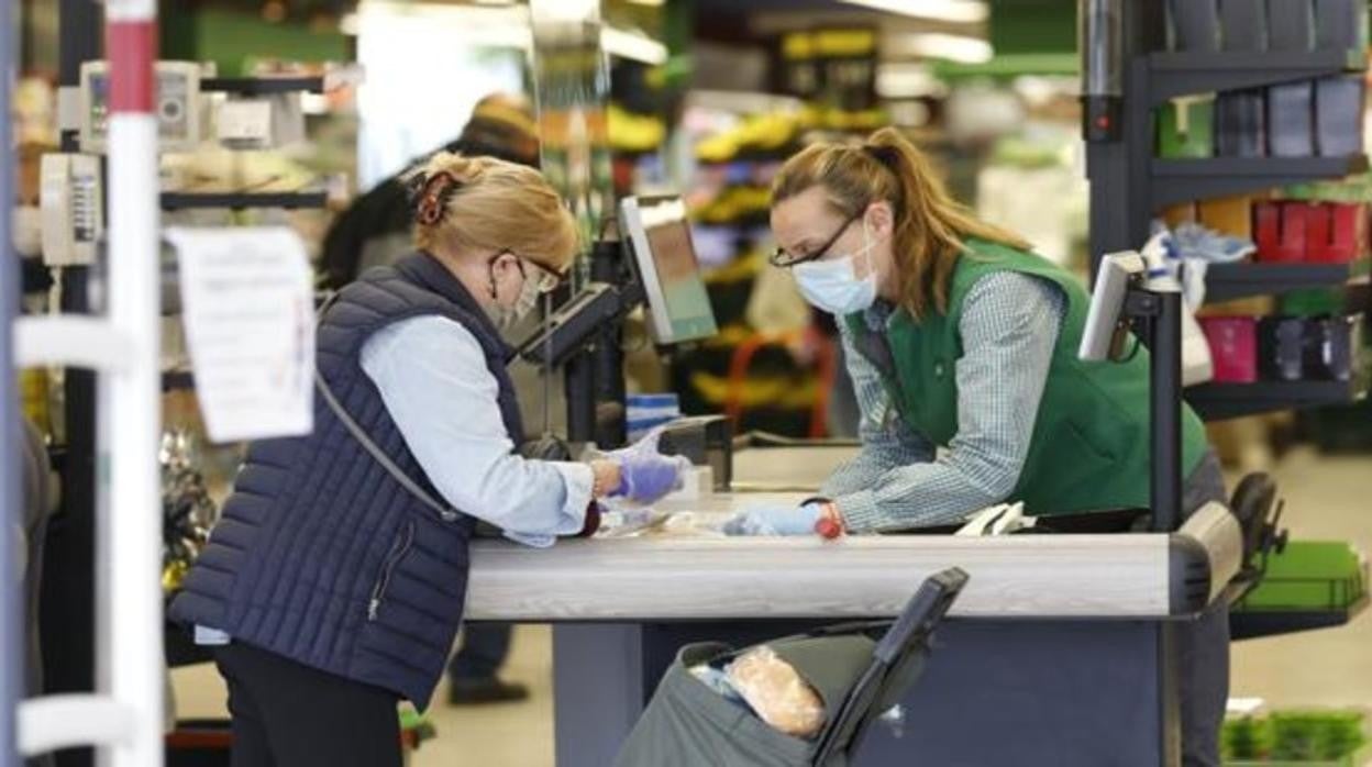 Una empleada de caja de Mercadona atendiendo a una clienta