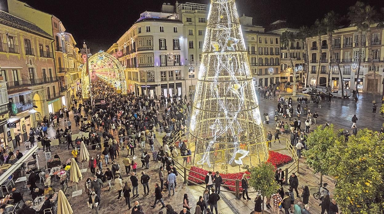 Ciudadanos pasean por el centro de Málaga iluminada para la Navidad