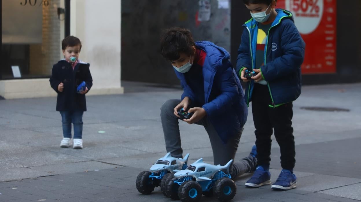 Dos niños juegan hoy con coches teledirigidos en el Centro de Córdoba