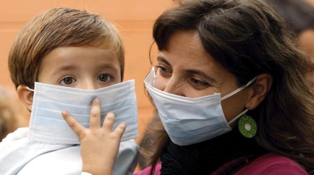 Un niño con la mascarilla puesta en brazos de su madre