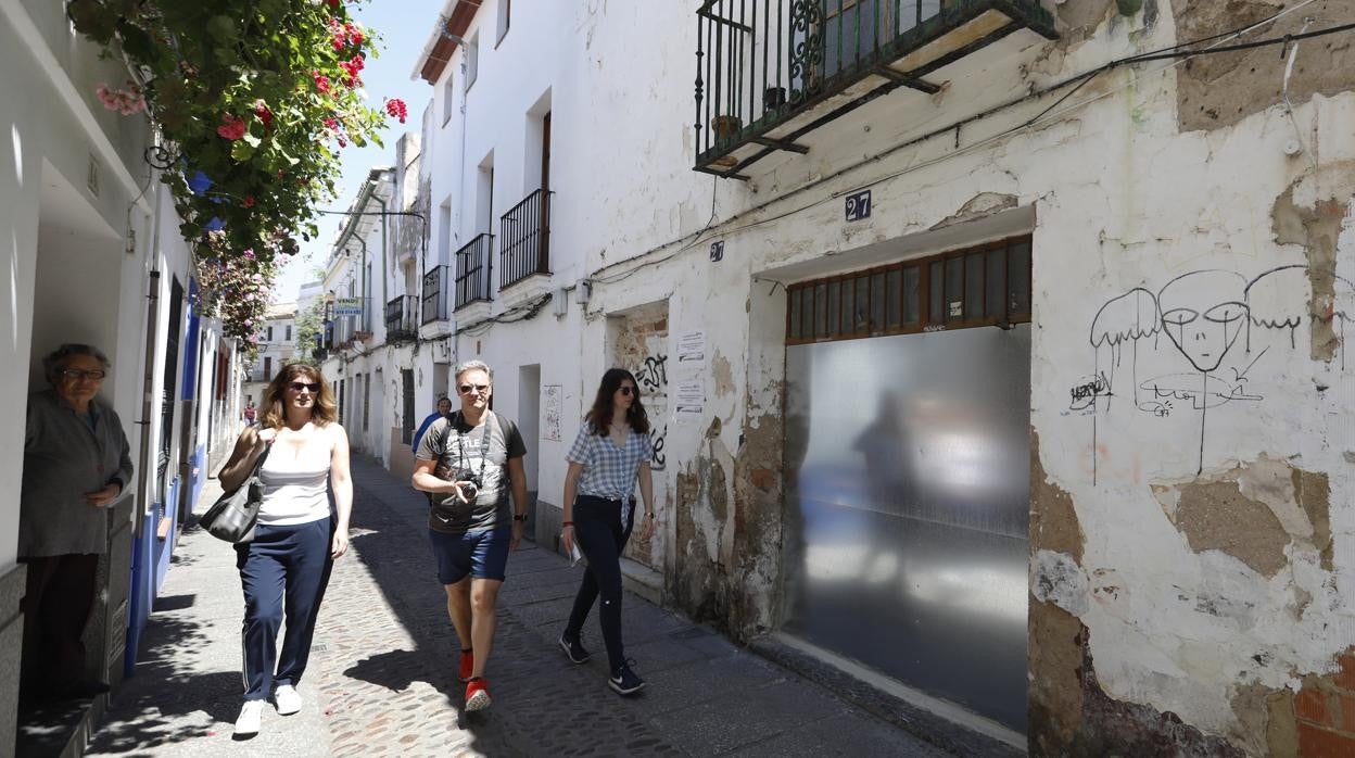 Casas cerradas en la calle Armas al paso de turistas y con una residente mayor