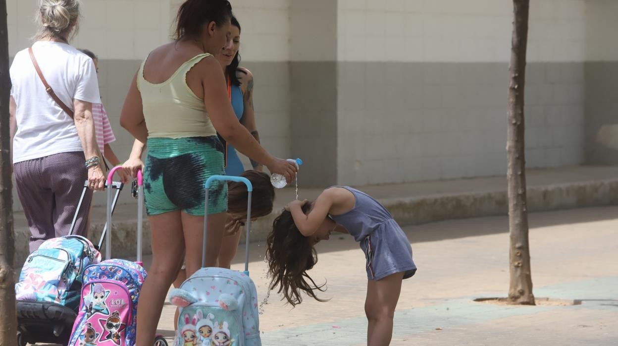 Una madre refresca a su hija después de sumarse a la protesta de padres del colegio Mediterráneo