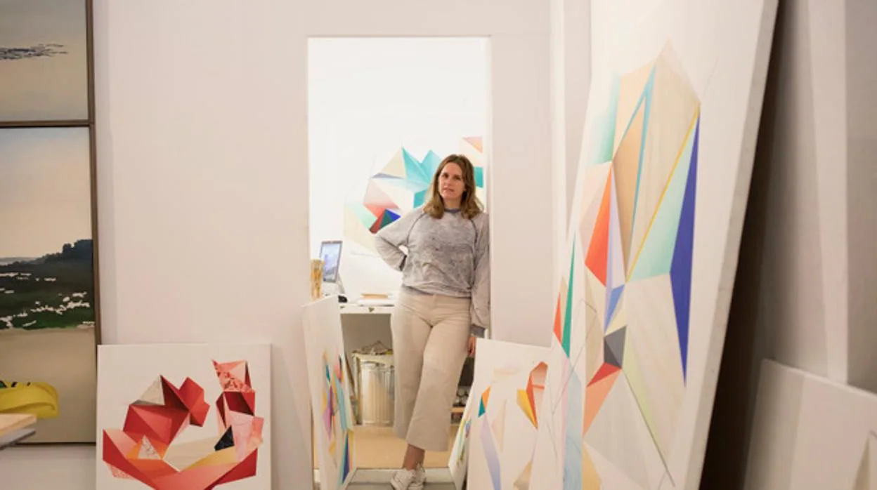 La artista sevillana Ángela Mena posa junto a una de sus obras pictóricas