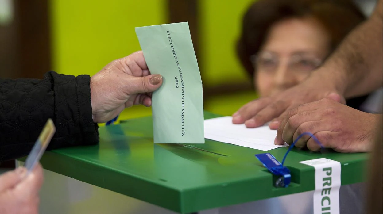 Un votante introduce su sobre en la urna, debidamente precintada