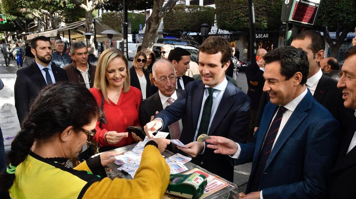 Casado compra un décimo de la ONCE mientras pasea por el centro de Almería junto a Juanma Moreno y otros candidatos al Parlamento andaluz