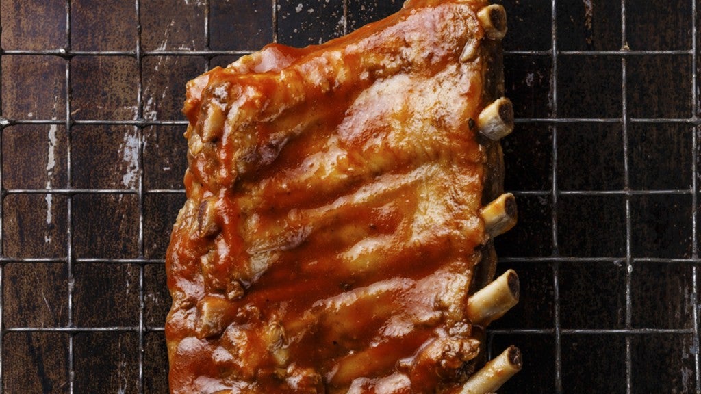 BBQ grilled smoked pork ribs on dark metal baking sheet backgrou. 