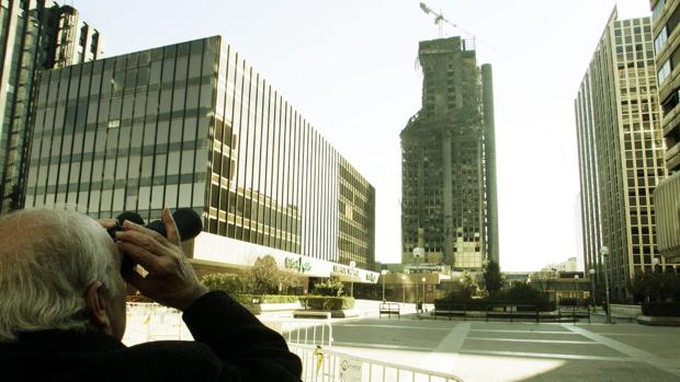 Un anciano observa con unos prismáticos el estado de un edificio quemado en Madrid
