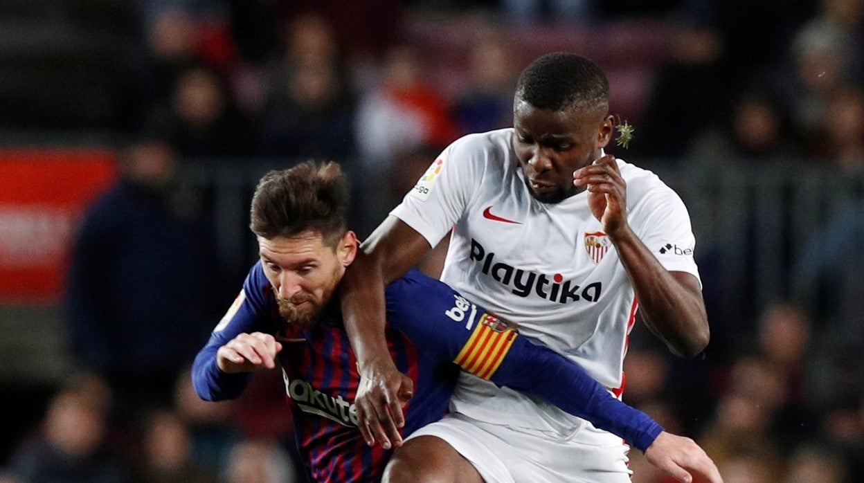 Amadou pelea un balón con Messi en un partido con el Sevilla