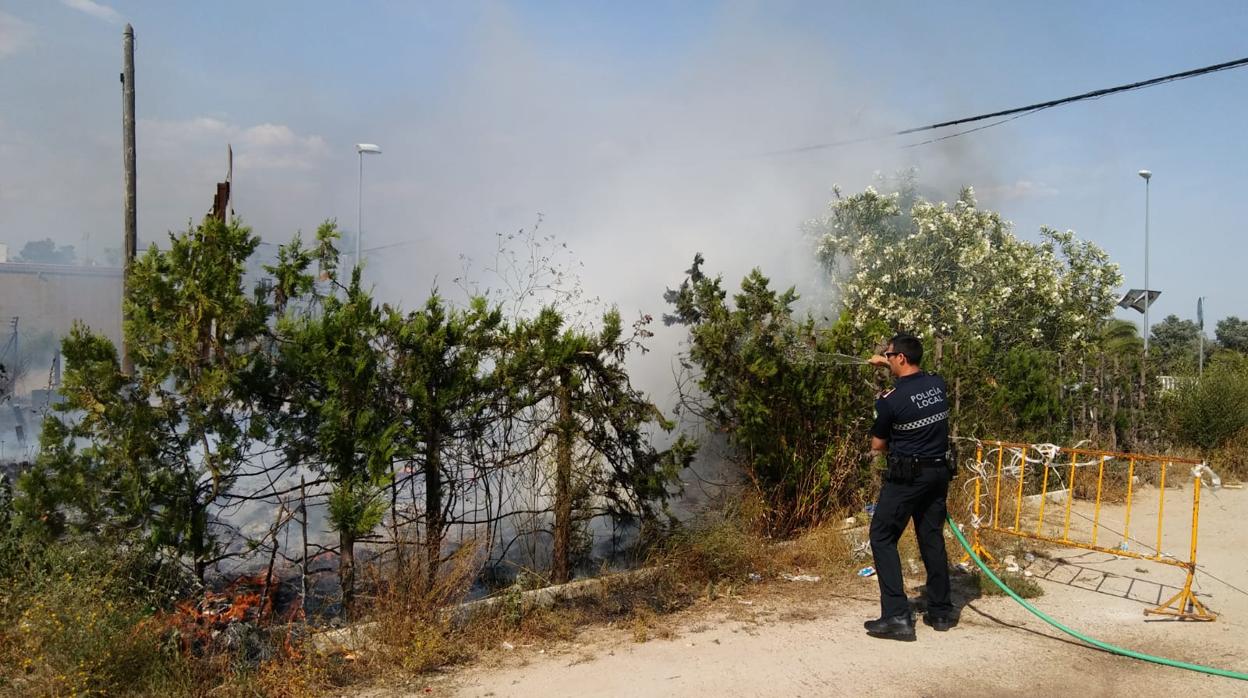 Un policía local de Coria apaga un fuego con la manguera de un particular ante la ausencia de los bomberos