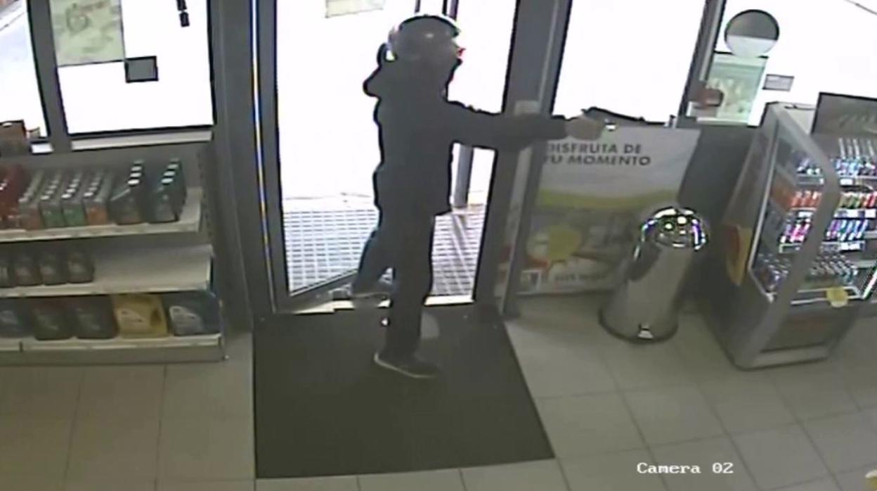 Encapuchado apuntando con una pistola a la empleada de la gasolinera