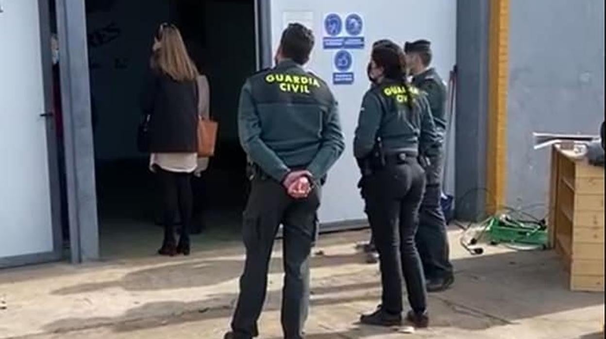 Agentes de la Guardia Civil esperan en la entrada de la nave de Agroalimentaria Los Lugares, en Marinaleda