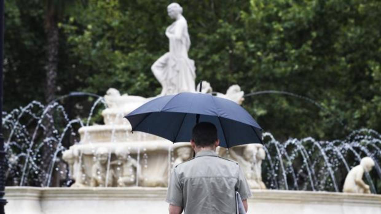 Un hombre se protege de las lluvias en Sevilla