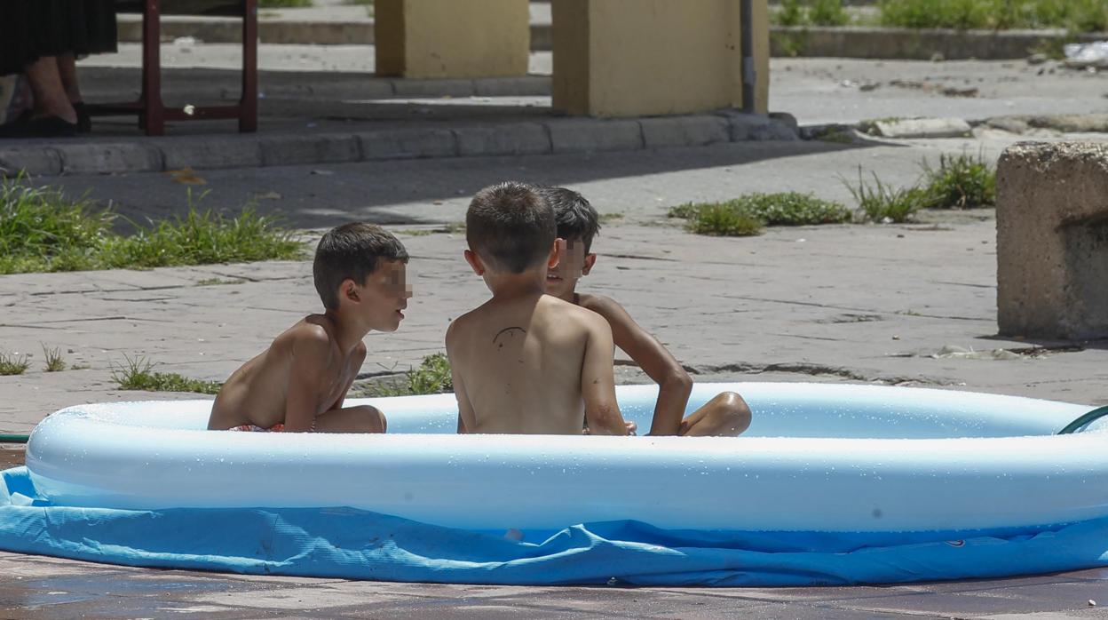 Unos niños juegan en una piscina de plástico en las calles del Polígono Sur