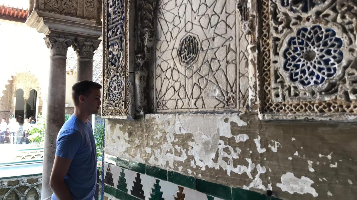 Un visitante observa el estado de las yeserías del Patio de las Doncellas