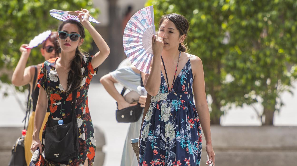 Dos turistas alivian el fuerte calor de Sevilla con unos abanicos