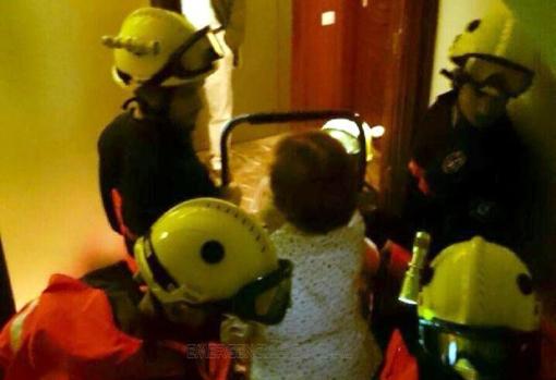 Los bomberos ayudan a levantarse a una anciana caída en el pasillo de su casa