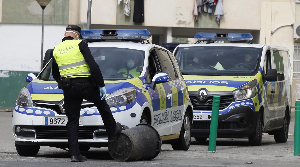 Un agente de la Policía Local aparta un cubo de basura en el Polígono Sur