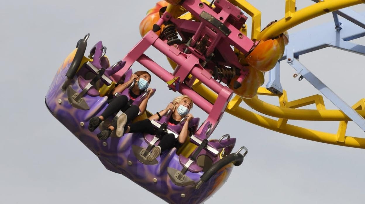 Dos jóvenes con mascarillas en una atracción