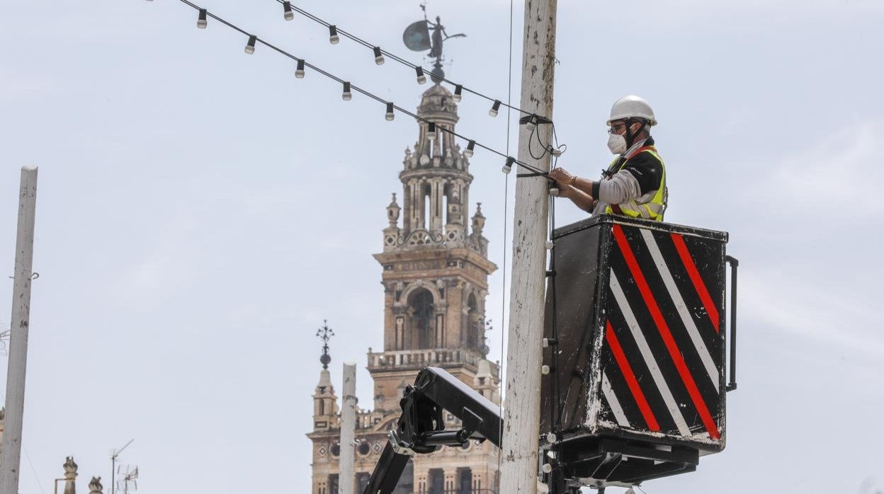 Un operario monta luces de Feria en la Plaza de San Francisco