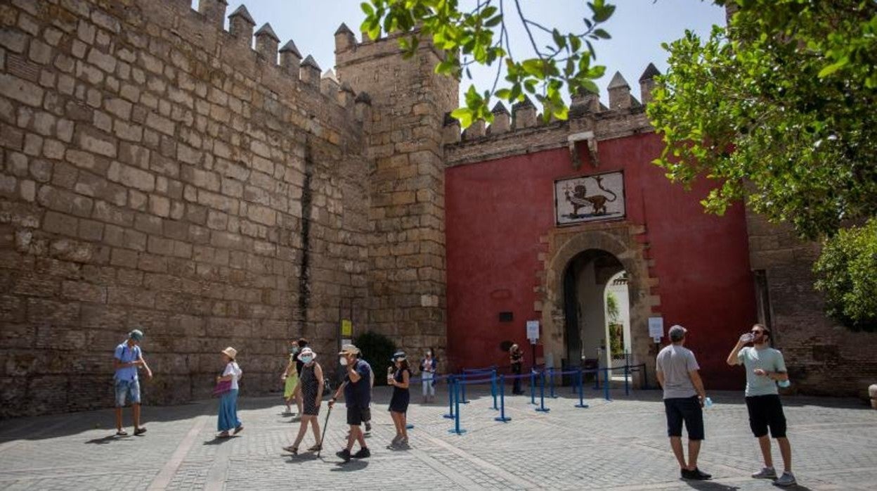 Varias personas protegidas con mascarillas pasean por los alrededores del Alcázar en Sevilla