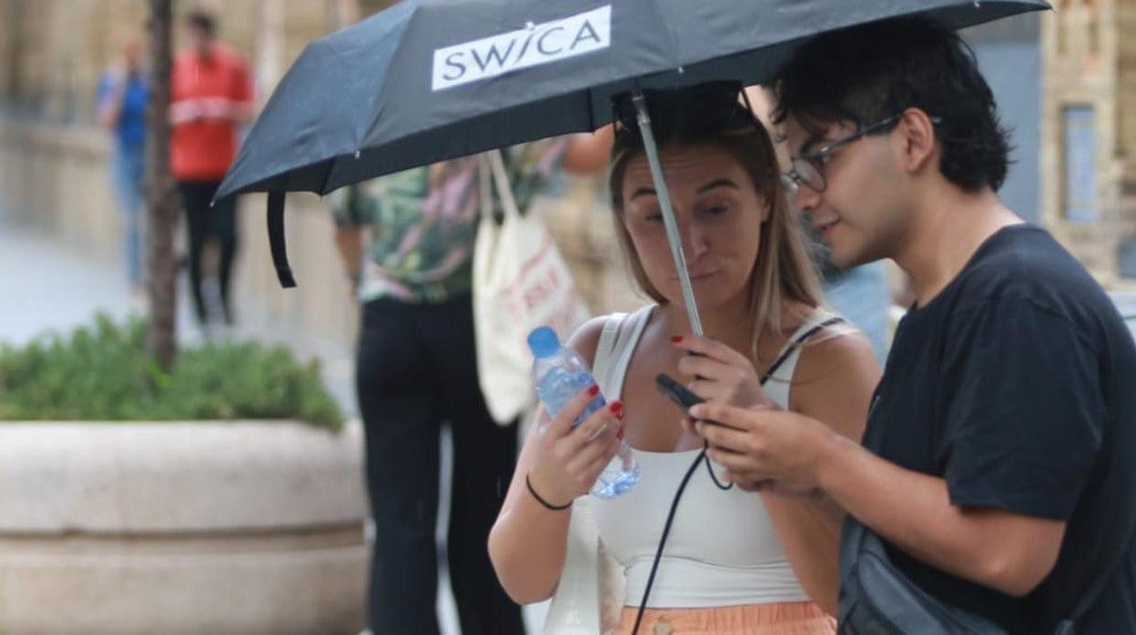 Dos personas se resguardan de la lluvia este jueves en Sevilla