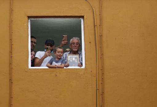Juan García asomado a la ventana con el cuadro de su madre