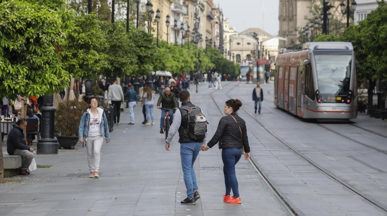 Viandantes atraviesan la Avenida con el tranvía de fondo