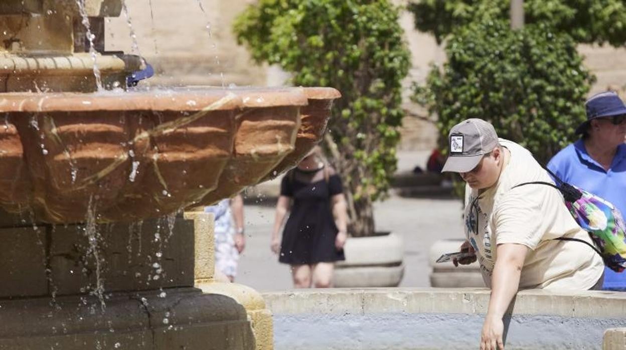 Una persona intenta refrescarse en una fuente de Sevilla para sofocar el calor