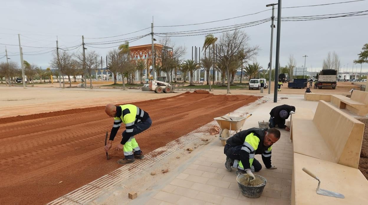 Operarios trabajan en la reforma de la calle del Potro en el recinto del Arenal con el montaje de la portada de la Feria de córdoba al fondo