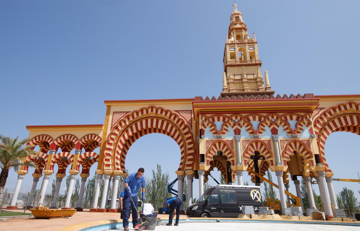 Operarios municipales limpian una de las fuentes instaladas en la zona de encuentro de la Feria bajo la portada