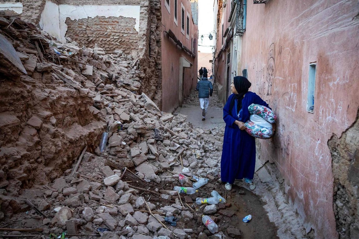 Un hombre camina con sus pertenencias entre los escombros en un callejón de la antigua ciudad de Marrakech, dañada por el terremoto