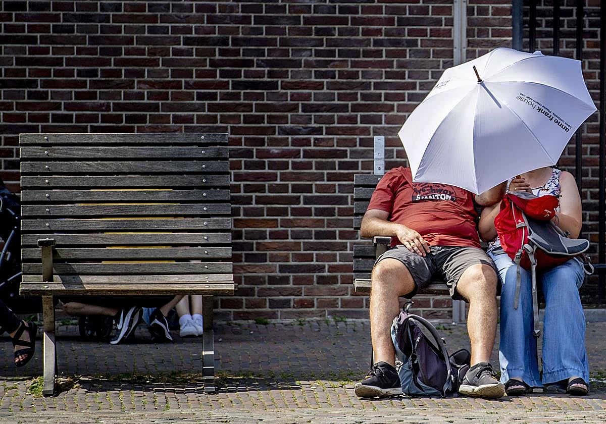 Una pareja se resguarda de los rayos de sol bajo un paraguas