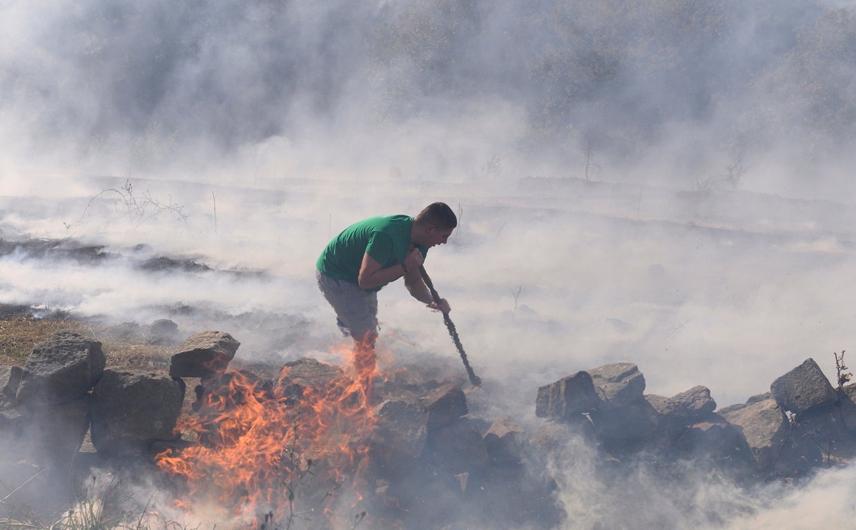 Vecinos de Bostronizo luchan contra el incendio forestal, declarado este sábado, en los montes de esta localidad Cántabra