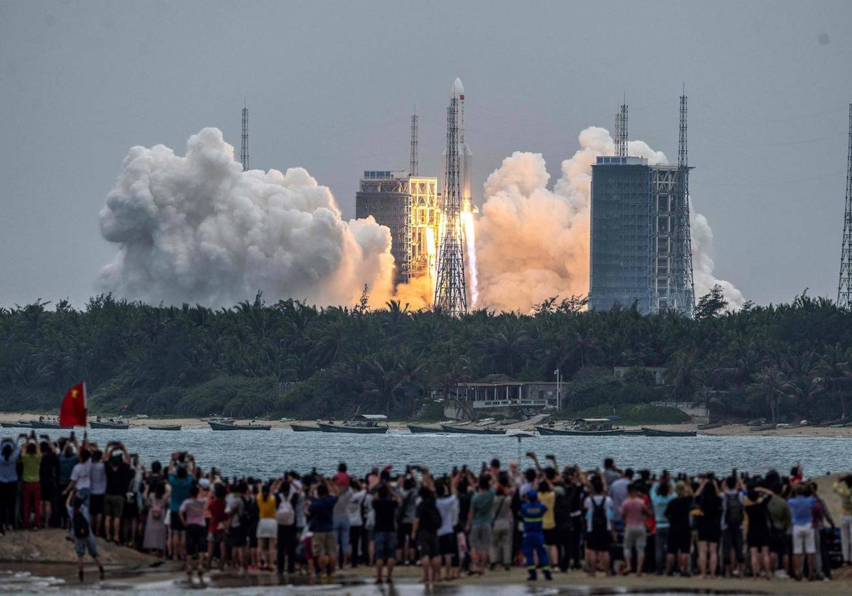 En esta foto tomada el 29 de abril de 2021, la gente observa un cohete Long March 5B, que transportaba el módulo central de la estación espacial Tianhe de China, mientras despega del Centro de Lanzamiento Espacial Wenchang en la provincia de Hainan, en el sur de China