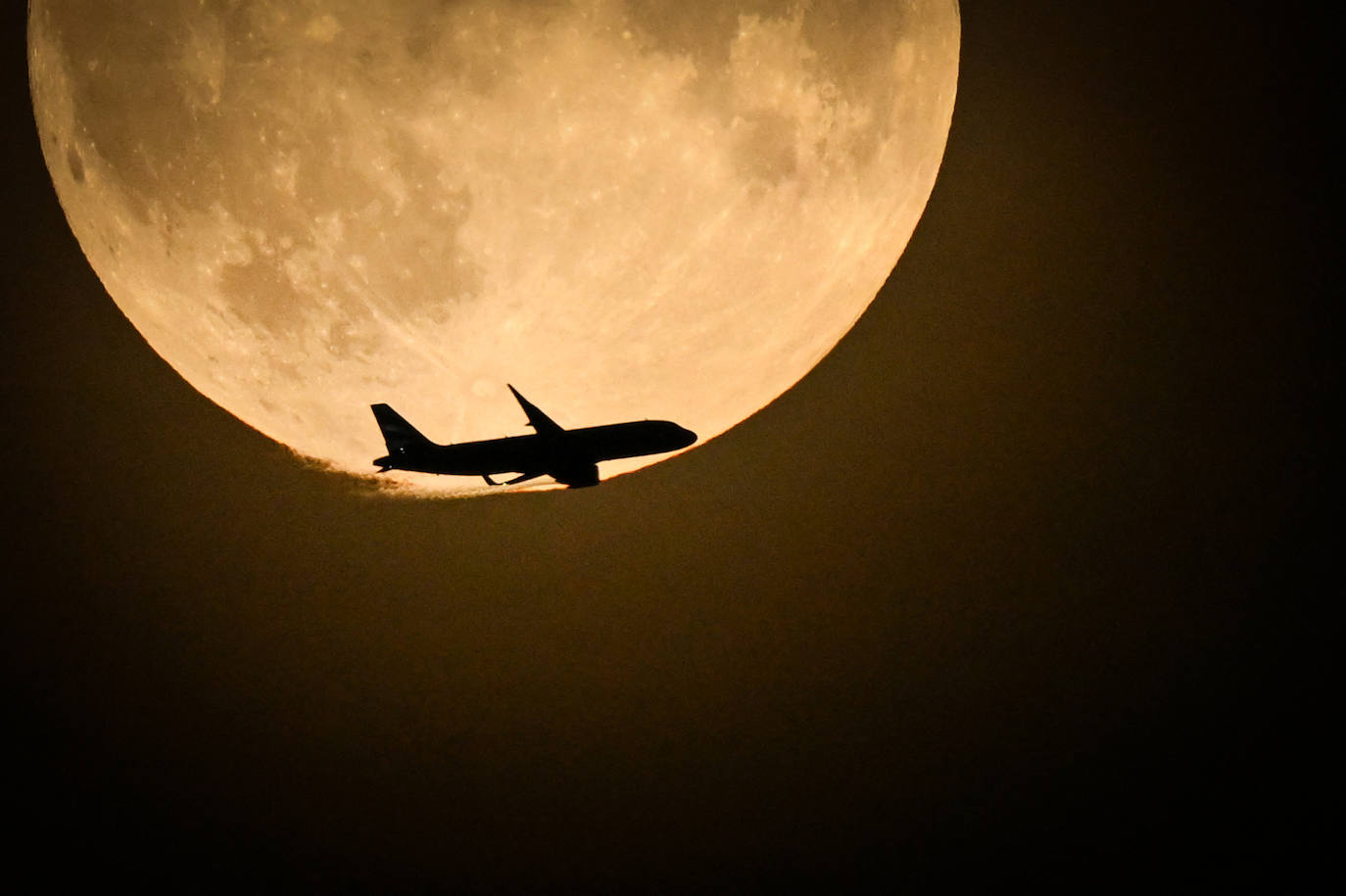 Un avión pasa junto a la Superluna Azul que se eleva en el cielo de Londres