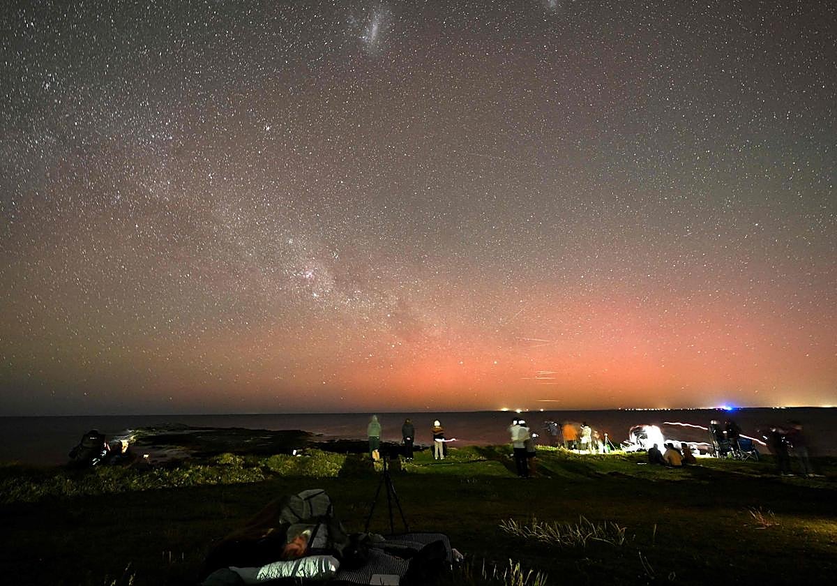 Observadores de estrellas se reúnen para ver la Aurora Australis, también conocida como las Luces del Sur, iluminando el cielo nocturno en Gerroa Headland en Kiama, a unos 133 kilómetros al sur de Sídney, el 12 de noviembre de 2025