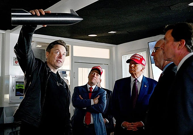 Elon Musk con un prototipo de Starship en la mano, ante la atenta mirada del presidente Donald Trump en la base de Boca Chica.