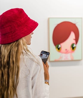 Imagen secundaria 2 - Arriba, detalle de la inauguración de CAN, la feria de Ibiza. Sobre estas líneas, Sergio Sancho, su director, y una joven tomando una foto con su móvil en el estand de Nanzuka