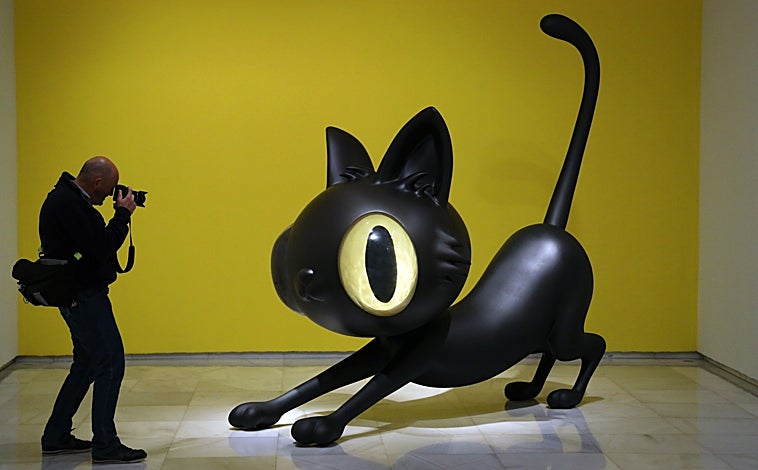 Imagen principal - Sobre estas líneas, algunas de las colaboraciones y 'toys' del artista. A la derecha, su 'pequeño Maurizio'. Arriba, un fotógrafo se afana con una escultura monumental del gato Gunter