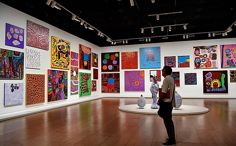 Imagen principal - Sobre estas líneas, 'Sala de espejos del infinito'. A la derecha, un hombre observa una de las obras colgadas en el Guggenheim. Arriba, detalle del montaje de la sección 'La fuerza de la vida'
