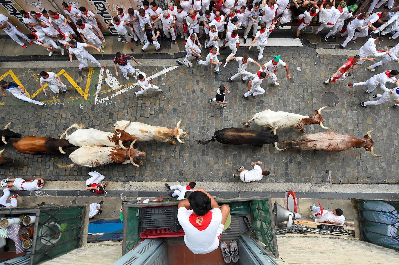 Un residente mira desde su balcón mientras los participantes corren con toros durante el primer «encierro» de las fiestas de San Fermín en Pamplona