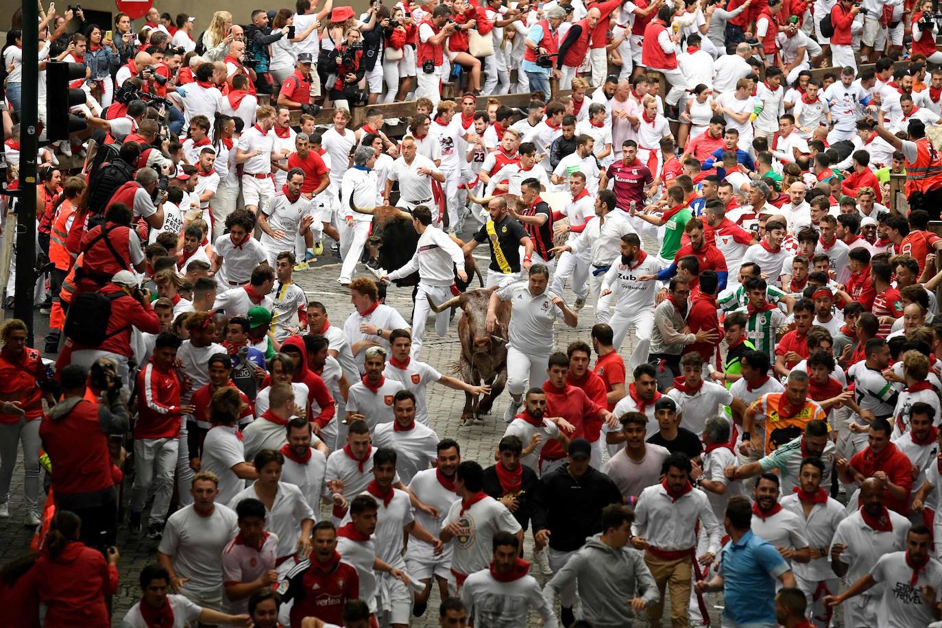 Los participantes corren delante de los toros durante el primer «encierro» de las fiestas de San Fermín en Pamplona