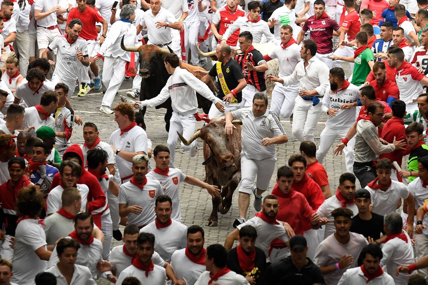 Los participantes corren delante de los toros durante el primer «encierro» de las fiestas de San Fermín en Pamplona